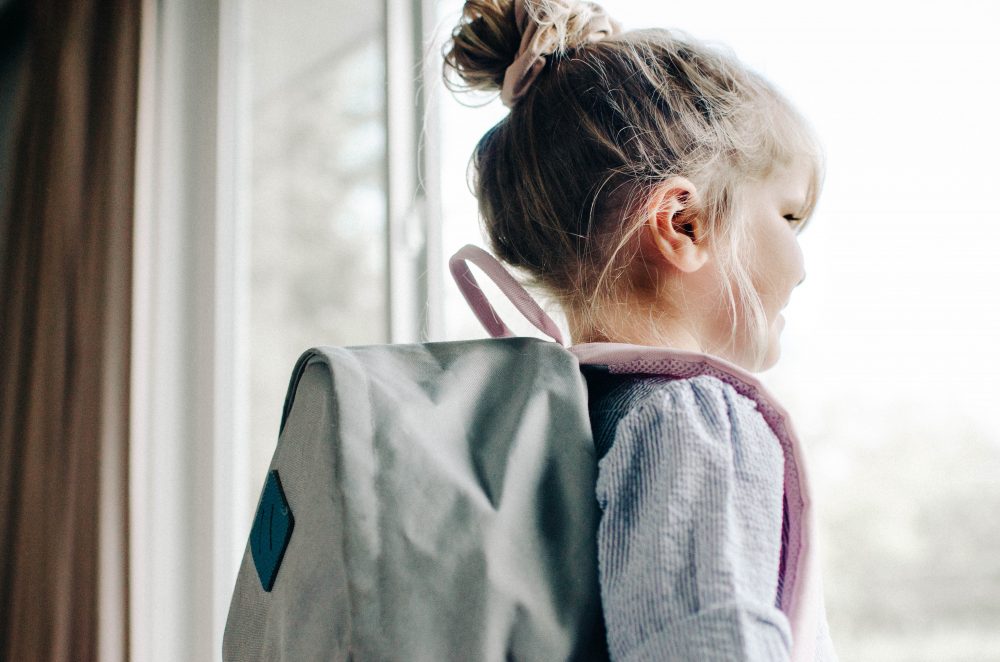 Girl with her back pack on looking outside for back-to-school